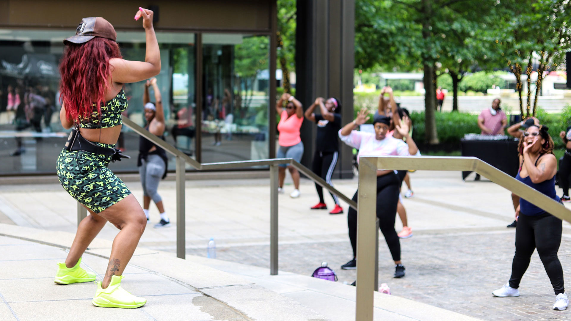 Queen D, Instructor of the BodyWERK fitness series, stands on stage leading workout class.
