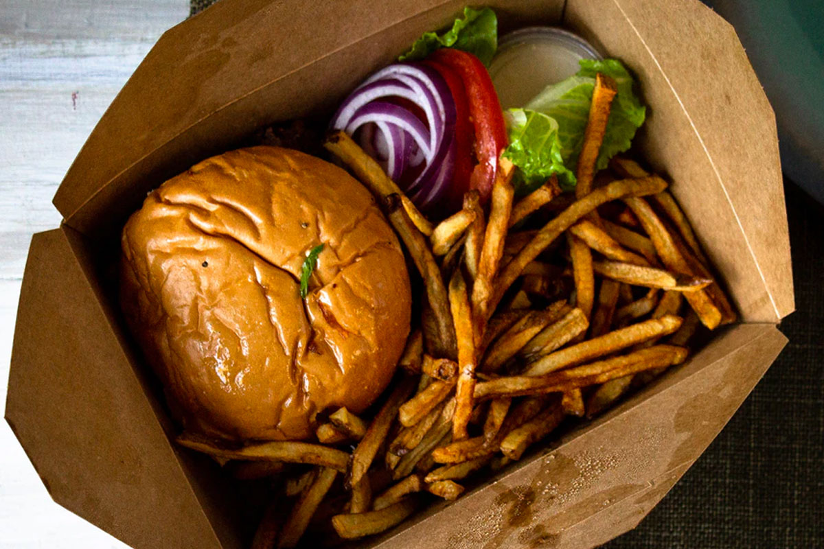 Burger and fries in brown cardboard takeout container.