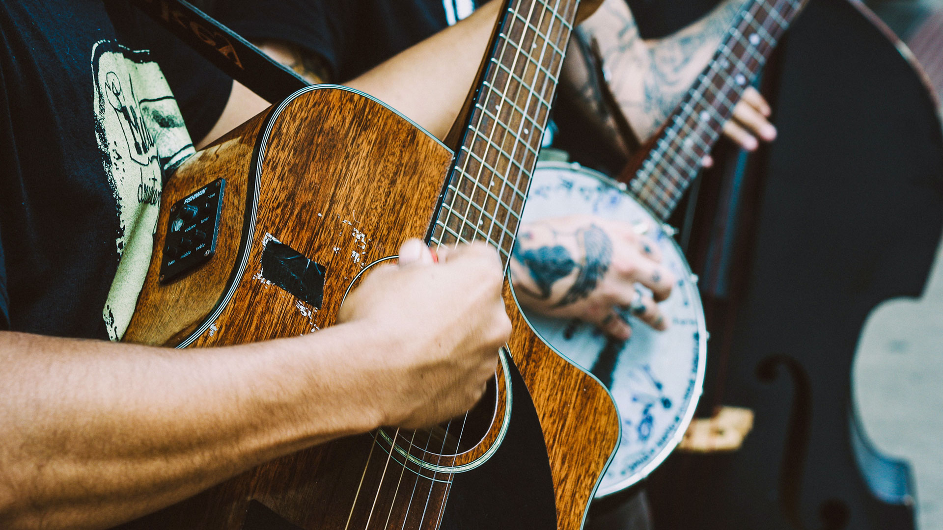 Close-up of guitarist strumming instrument.