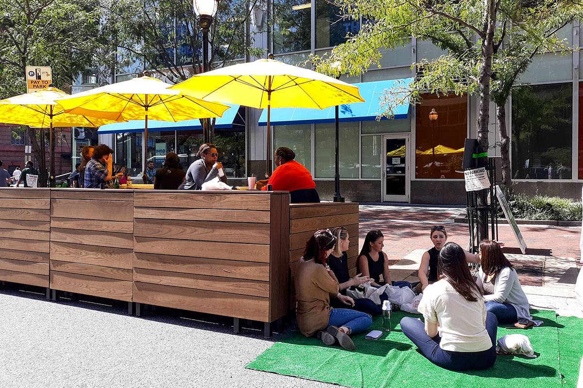 Downtown Partnership's outdoor "Parklet" featuring yellow umbrellas and tables.
