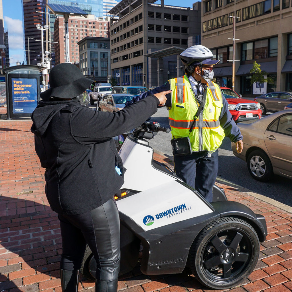 Uniformed guide on Segway helping pedestrian with directions in Downtown Baltimore.