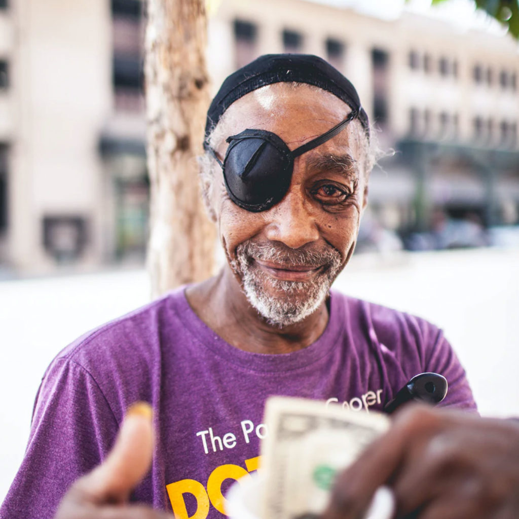 Homeless man smiling and holding a 'thumbs up.'