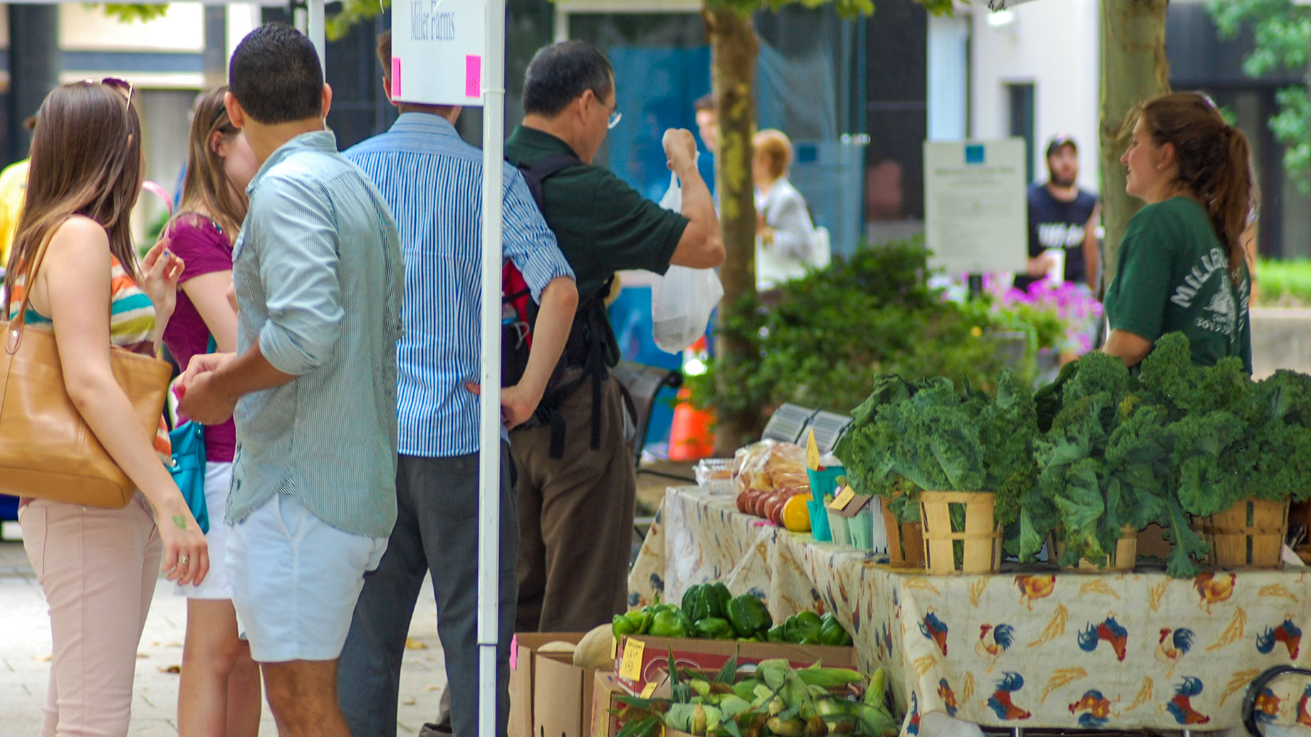 Couple at farmers' market in front of produce stand.