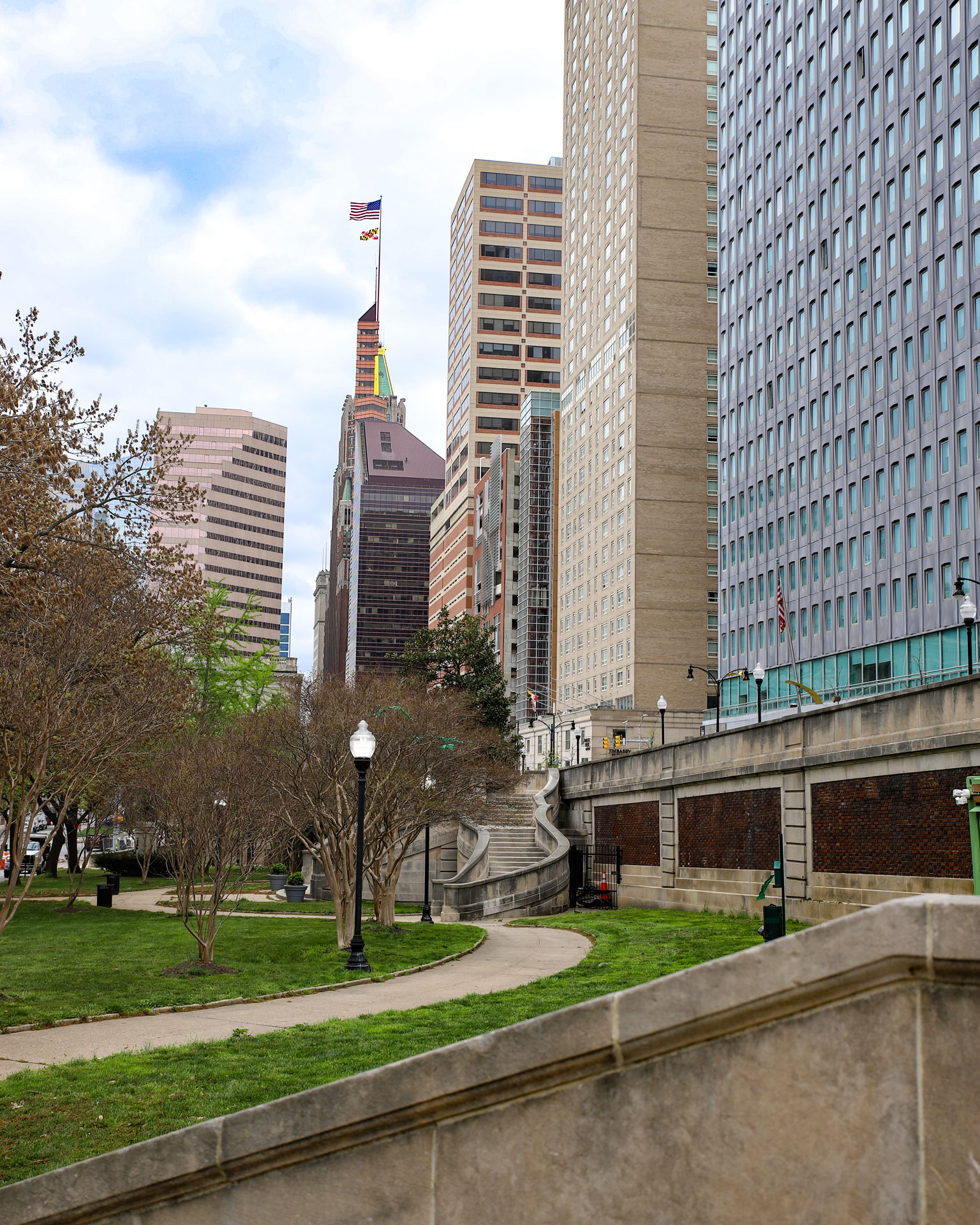 Green park space of Preston Gardens with Downtown Baltimore buildings in the background.
