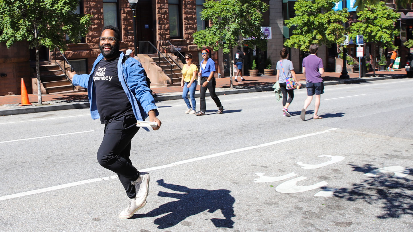 Man joyfully skipping in the road during the Charles Street Promenade