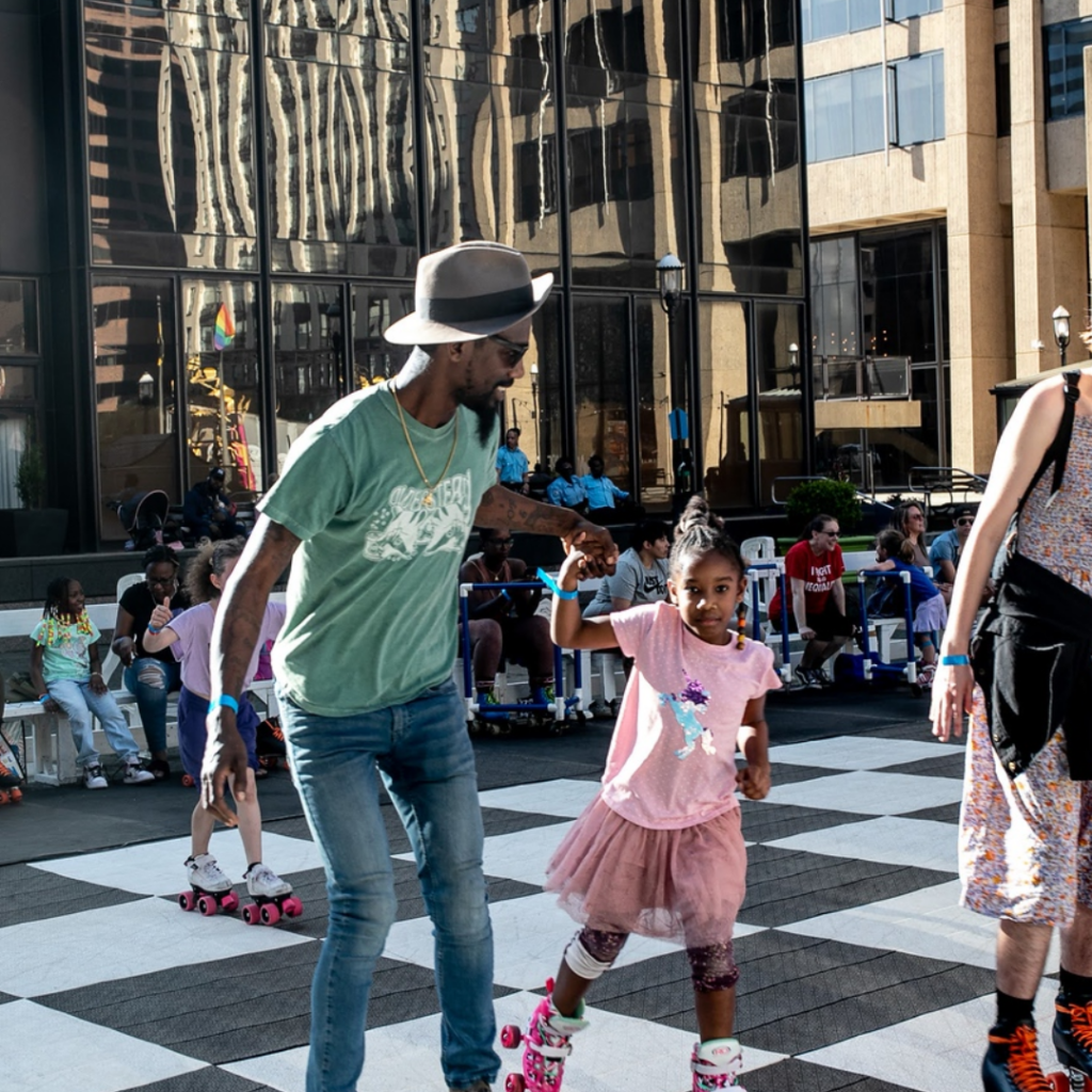 Young girl and father roller skate in Downtown Baltimore.
